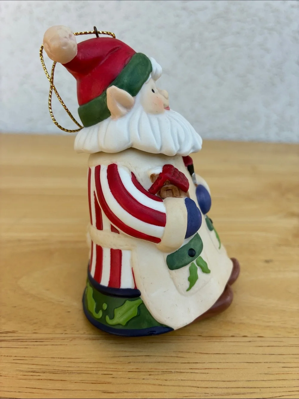 Ceramic elf painting a bird house bell ornament with little floppy legs